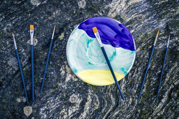 Painted ceramic plate and paintbrushes on mossy stone background stock photo