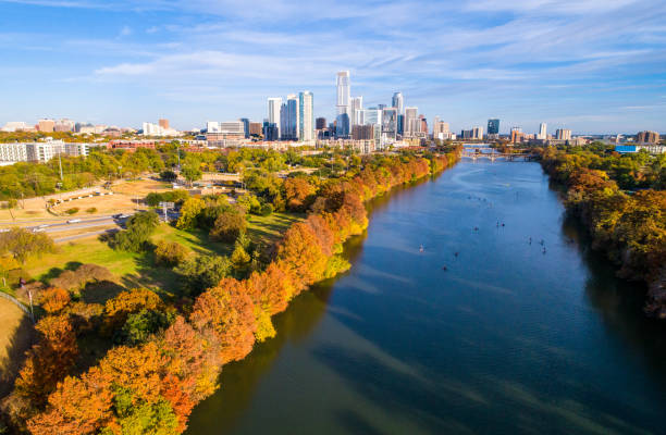 Austin Texas fall colors autumn leaves along Colorado river Austin Texas above lady bird lake , as leaves change during autumn fall colors dramatic line of trees along shore with Austin Texas skyline cityscape downtown skyscrapers in background colorado river photos stock pictures, royalty-free photos & images