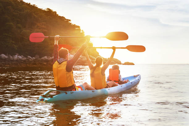 familia feliz en kayak isla del mar al atardecer a pie - kayak barco de remos fotografías e imágenes de stock