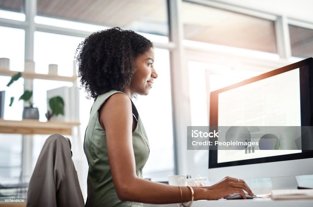 Handling her workload with ease Shot of a young businesswoman working at her desk in a modern office Computer Monitor Stock Photo