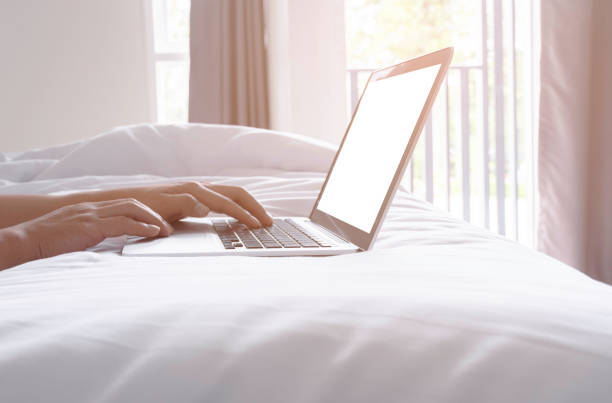 man using laptop working on bed stock photo