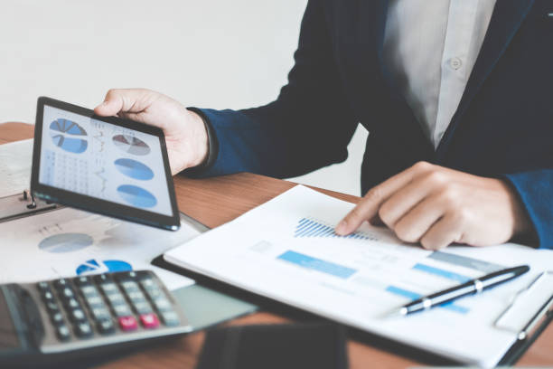 istock Businessman hands using text information on digital tablet to analyze financial statistical chart data and calculate cost of investment project 1071652042