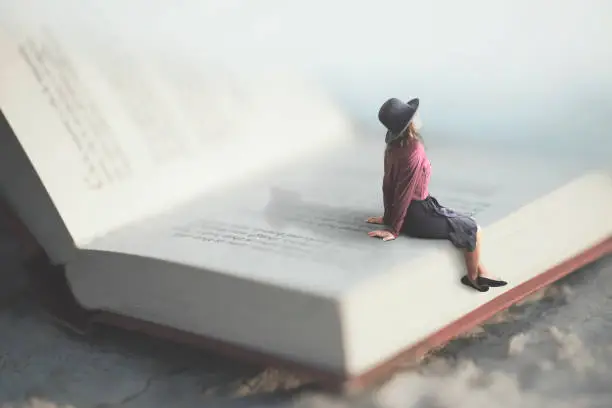 surreal moment of a woman relaxes sitting on a giant book