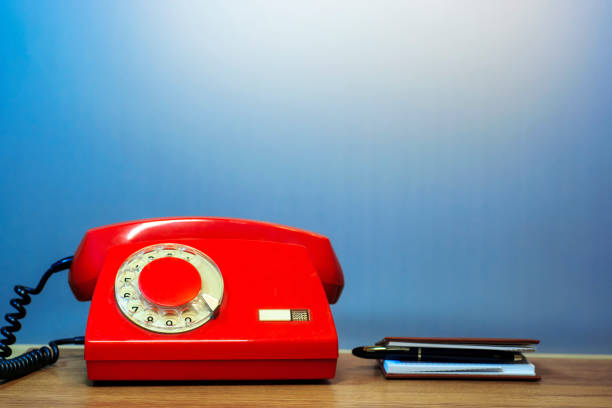 Outdated red rotary dial telephone The outdated once-fashionable rotating red disc phone and phone book интерьер помещений stock pictures, royalty-free photos & images