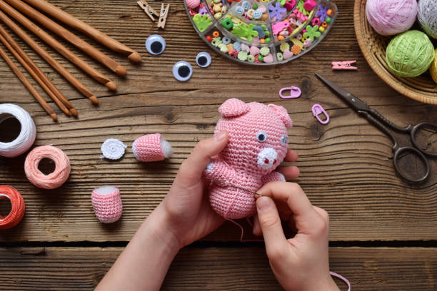 istock Making pink pig. Crochet toy for child. On table threads, needles, hook, cotton yarn. Step 2 - to sew all details of toy. Handmade crafts. DIY concept. Small business. Income from hobby 1071670652
