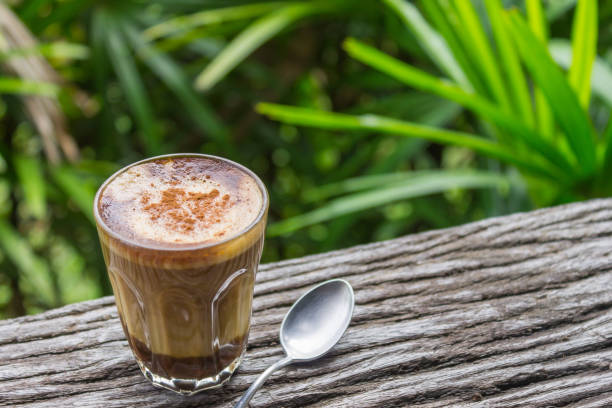 istock Latte Coffee in Glass with Spoon on Wood Table on Tree Background Left 2 1071674200