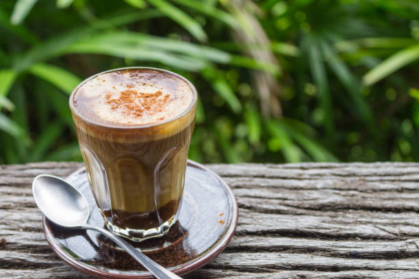 istock Latte Coffee in Glass with Spoon on Wood Table on Tree Background Left Zoom 1071674240