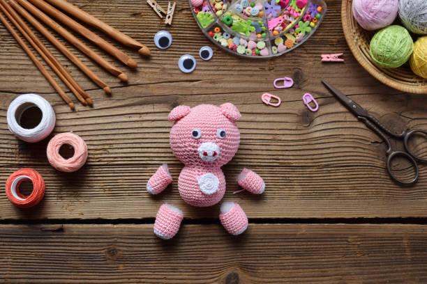istock Making pink pig. Crochet toy for child. On the table threads, needles, hook, cotton yarn. Step 1 - knit all details of toy. Handmade crafts. DIY concept. Small business. Income from hobby 1071674460