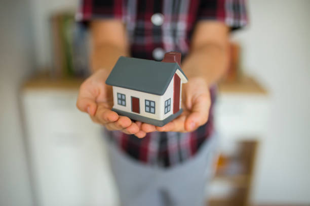istock Young boys hands holding a model house 1071675428