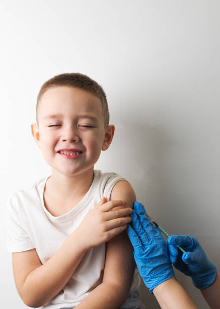 young boy doesn't want to do medical injection, placing him hand in a stop jestuge. afraid of vaccination. boy and a doctor with a syringe in his hands in blue gloves. vaccination concept, preventional immunization. - russian influenza epidemic virus flu virus imagens e fotografias de stock