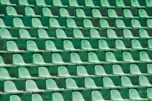 Empty green plastic spectators seats closeup on tennis court stand