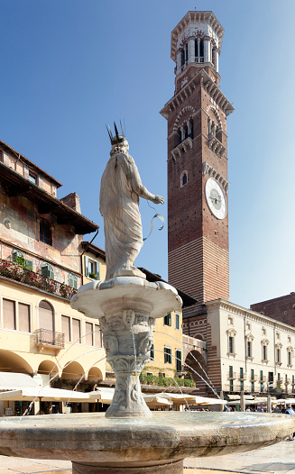 Verona, Italy -October 21,2018: The square's most ancient monument is the fountain built in 1368 by Cansignorio della Scala, surmounted by a statue called Madonna Verona, which is however a Roman sculpture dating to 380 AD. In the background the Lamberti tower.