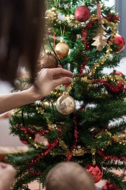 istock Mother placing golden holiday bauble on Christmas tree 1071694980