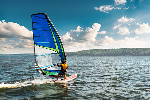 the man athlete rides the windsurf over the waves on the lake