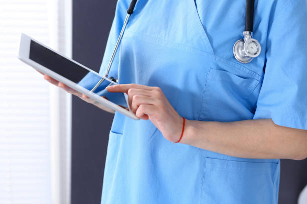 istock Woman doctor using tablet computer while standing straight in hospital office, closeup. Healthcare, insurance and medicine concept 1071706232