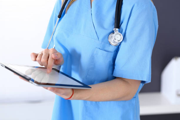 istock Woman doctor using tablet computer while standing straight in hospital office, closeup. Healthcare, insurance and medicine concept 1071706240