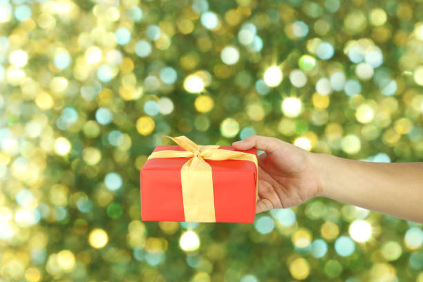 istock Red Gift Box on hand for Christmas concept with green blur bokeh background. 1071717624