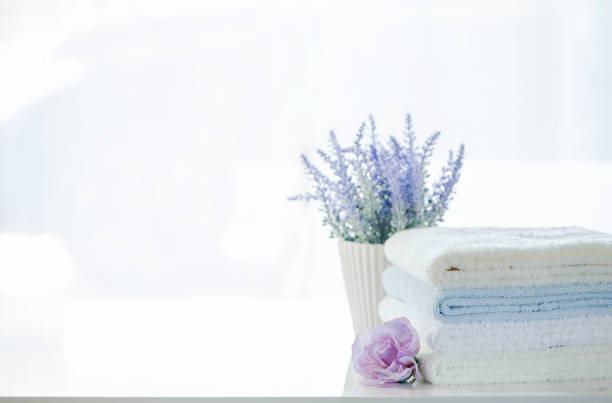 Mockup stack of white towels and flower on white table with copy space.