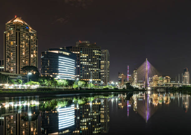 istock Night skyline with buildings reflecting in river with cable-stayed bridge in background, Sao Paulo, Brazil 1071724670