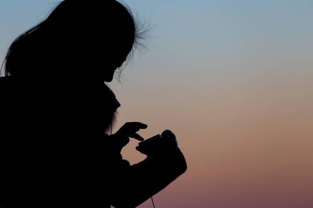 A girl in silhouette  with a mobile phone in her hand