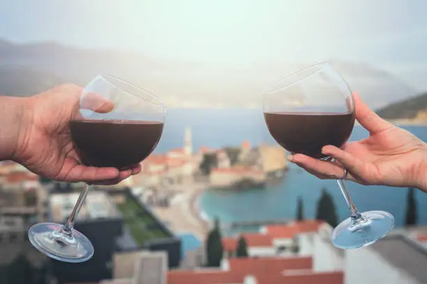 Photo of Man and woman holding glasses with red wine