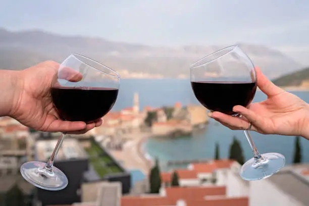 Photo of Man and woman holding glasses with red wine