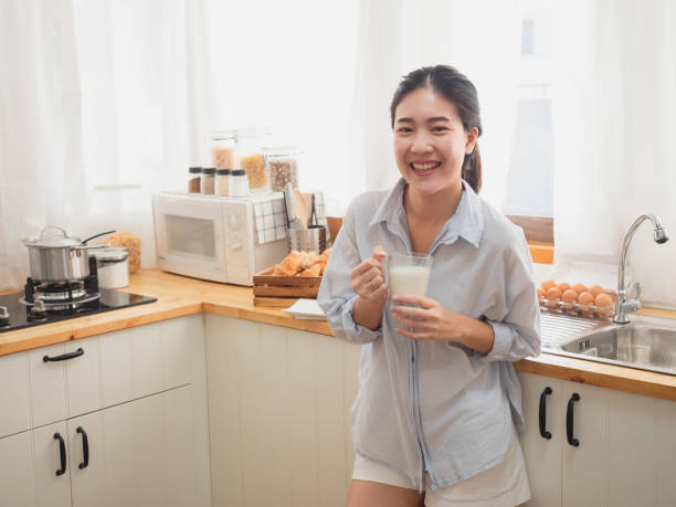 istock asian woman drink milk  in the kitchen 1071733438