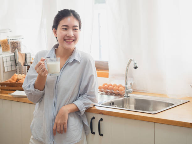 istock asian woman drink milk  in the kitchen 1071733564
