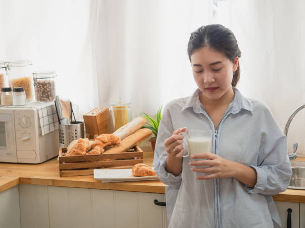 istock asian woman drink milk  in the kitchen 1071733700