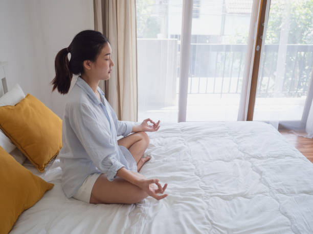 istock Young asian woman sitting and practicing doing yoga on bed 1071736056