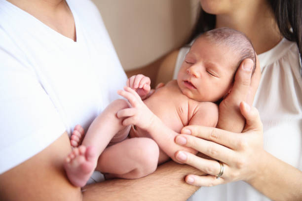 Hands of Father and Mother Holding Newborn Baby stock photo