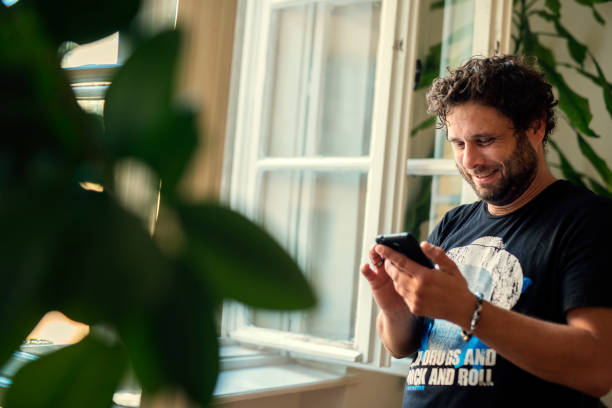 istock Cheerful young man texting and browsing the internet on his smart phone 1071751228