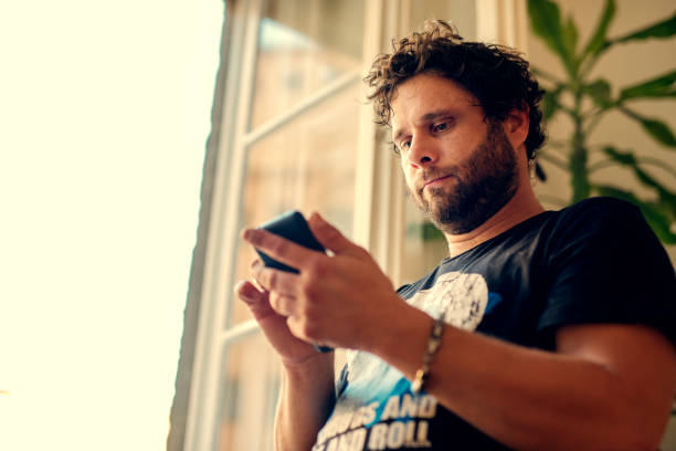 istock Cheerful young man texting and browsing the internet on his smart phone 1071751254