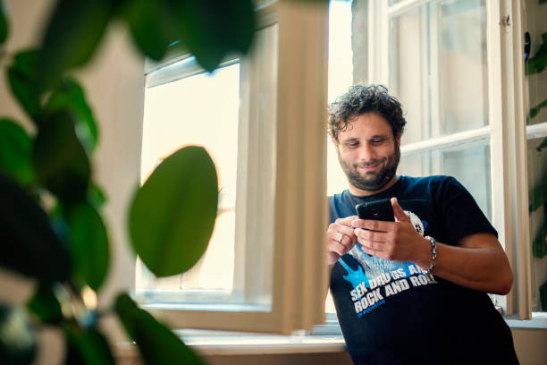 istock Cheerful young man texting and browsing the internet on his smart phone 1071751322