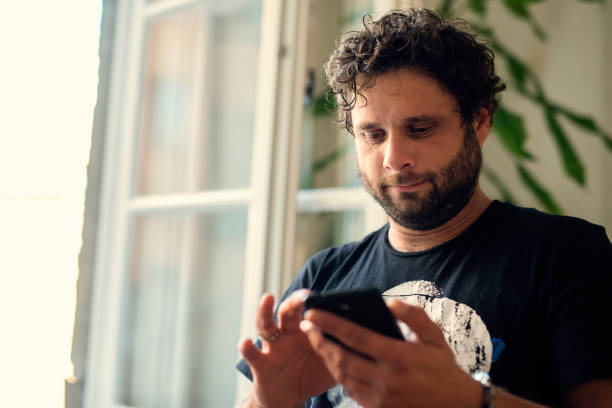 istock Cheerful young man texting and browsing the internet on his smart phone 1071751324