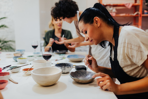 Group of women enjoying on ceramics workshop. Painting a bowl and enjoying.
