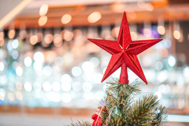Red star decoration on the three with blur big Christmas tree behide.