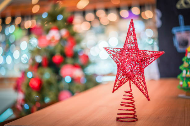 istock Red star decoration on the wood table with blur big Christmas tree behide. 1071762050