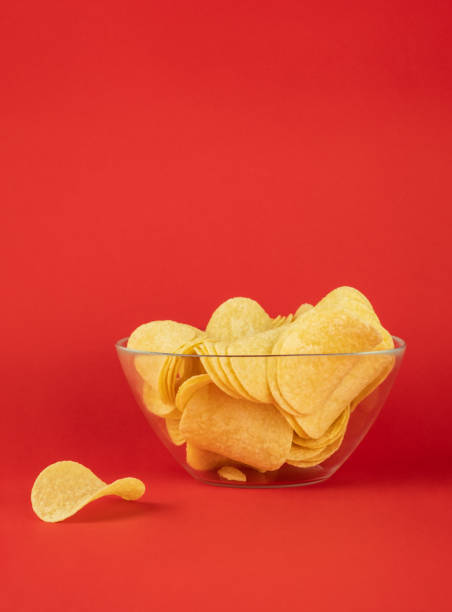 istock Bowl of potato chips in bright red background 1071768482