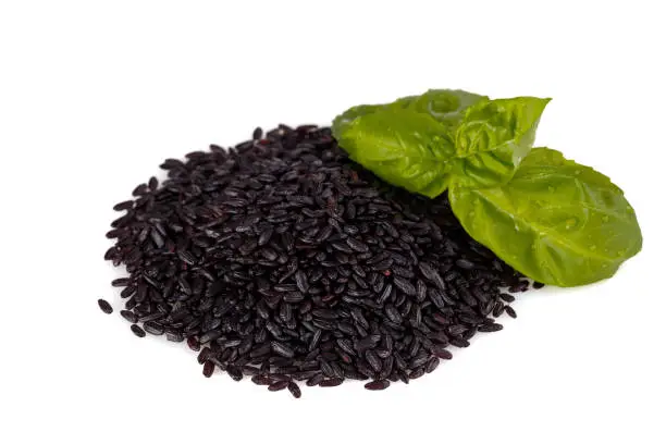 bunch of black rice on a white background with basil