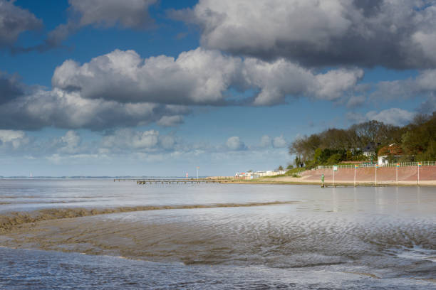 Dangast, Germany - May 3, 2016: Low tide in wadden sea. Blue sky with cumulus clouds on sunny day in springtime. Camping site in background. The village is a travel destination in the German North Sea Region and known for art and craft.