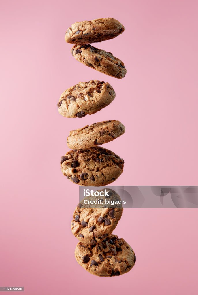 Chocolate chip cookies falling in stack Chocolate chip cookies falling, pink background, food levitation Cookie Stock Photo