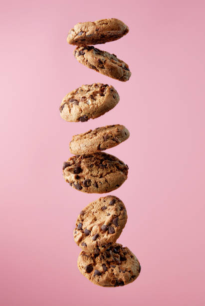 Chocolate chip cookies falling in stack Chocolate chip cookies falling, pink background, food levitation milk photos stock pictures, royalty-free photos & images