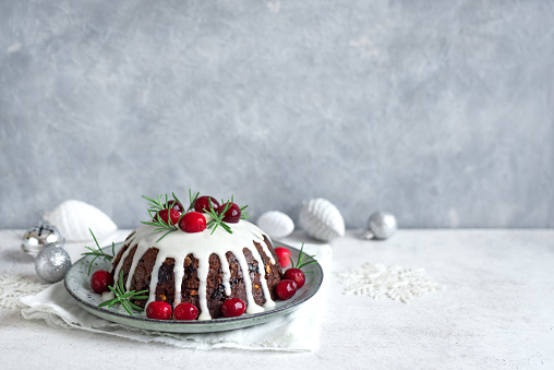 Christmas Pudding, Fruit Cake decorated with icing and cranberries on white table, copy space. Homemade traditional christmas dessert - Christmas Pudding.