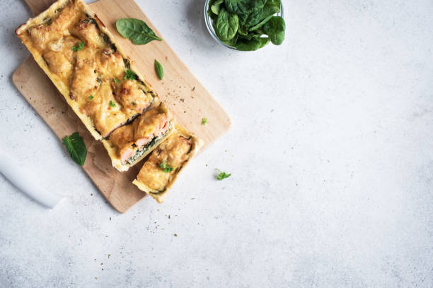 Salmon Spinach Pie (quiche) Salmon Spinach Pie (quiche) with cheese on white background. Homemade salmon tart for healthy lunch, top view, copy space. fish pie stock pictures, royalty-free photos & images