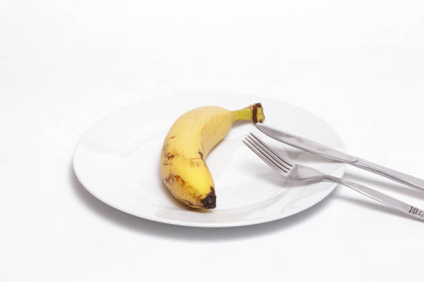 istock Banana and cutlery on a white dish against white background 1071787440