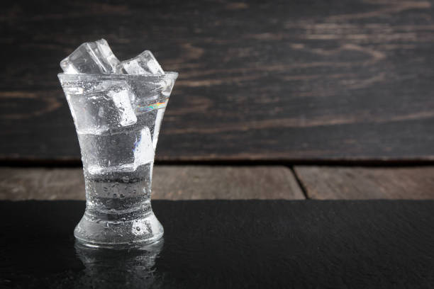 bicchiere di vodka russo con ghiaccio su un tavolo di legno scuro - russian shot foto e immagini stock