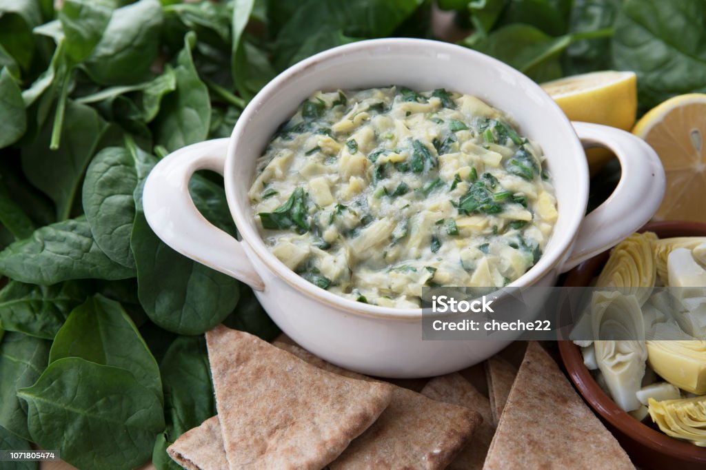 Spinach Artichoke Dip with Fresh Ingredients Bowl of vegan spinach artichoke dip with pita and ingredients. Dipping Sauce Stock Photo