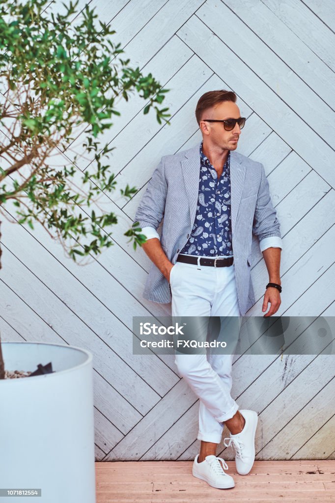 Hombre De Moda En Gafas De Sol Vestidos Con Ropa Elegante Moderna Contra La  Pared De Madera Blanca Foto de stock y más banco de imágenes de A la moda -  iStock