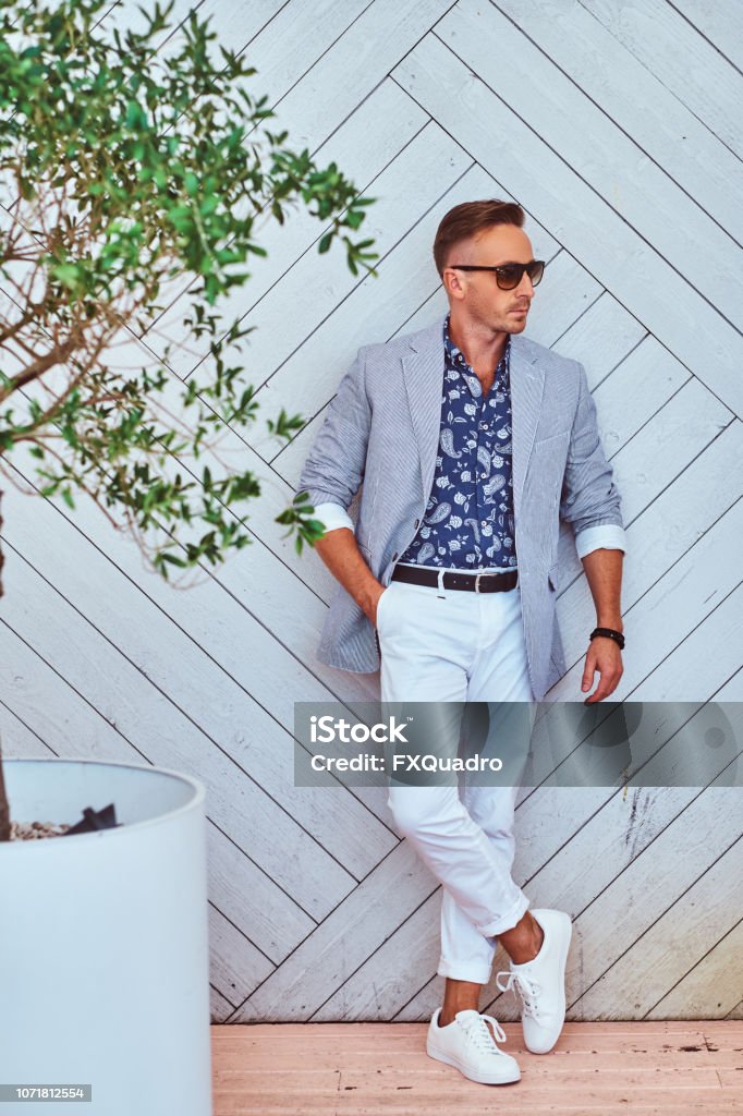 Hombre De Moda En Gafas De Sol Vestidos Con Ropa Elegante Moderna Contra La Pared De Madera Blanca Foto de stock y más banco de imágenes de A la moda - iStock Hombre De Moda En Gafas De Sol Vestidos Con Ropa Elegante Moderna Contra La Pared De Madera Blanca Foto de stock y más banco de imágenes de A la moda - iStock